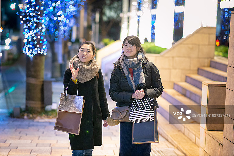 圣诞节的夜晚，女性朋友们走在购物街上图片素材