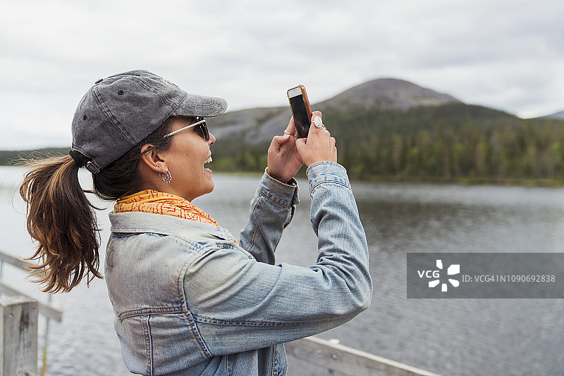 芬兰，拉普兰，快乐的女人在湖边的码头上自拍图片素材