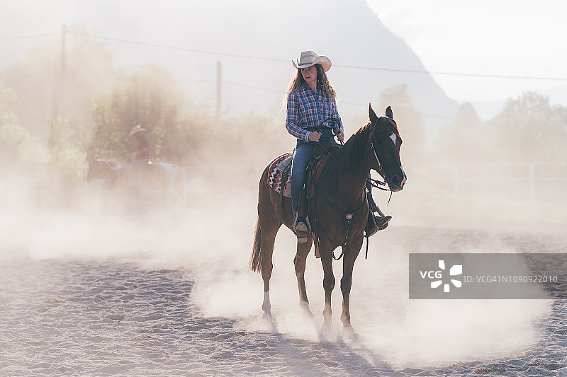 意大利特伦蒂诺-上阿迪杰，普里马卢纳，一个骑在尘土飞扬的马术场上的女牛仔图片素材