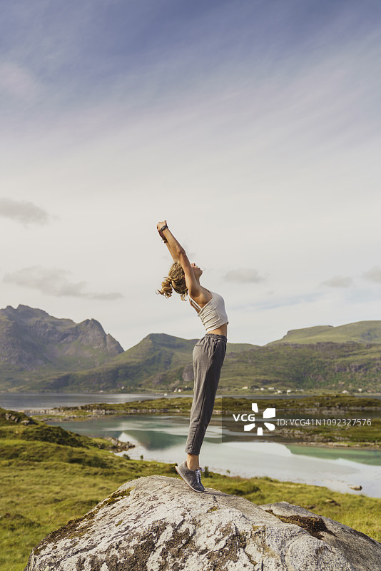 年轻女子站在大自然中，伸展身体，拉普兰，挪威图片素材