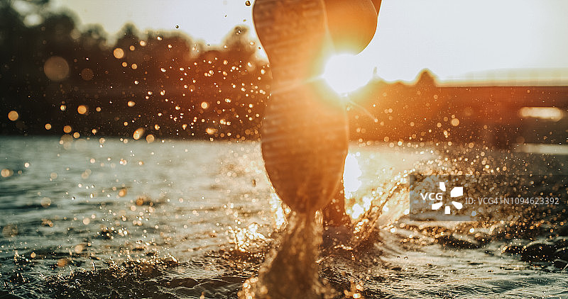 夕阳下，人在水里奔跑的脚步图片素材