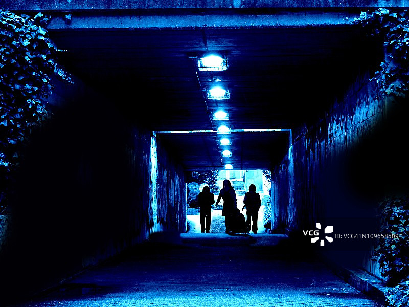 两个男人和一个女人在黑暗的隧道里。图片素材