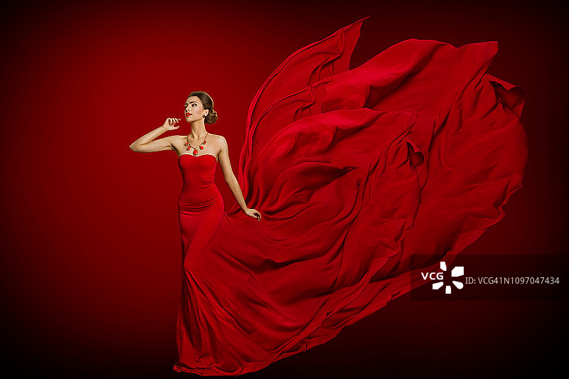 时装模特红色火红的裙子，女人在长飘扬挥舞长袍尾巴图片素材