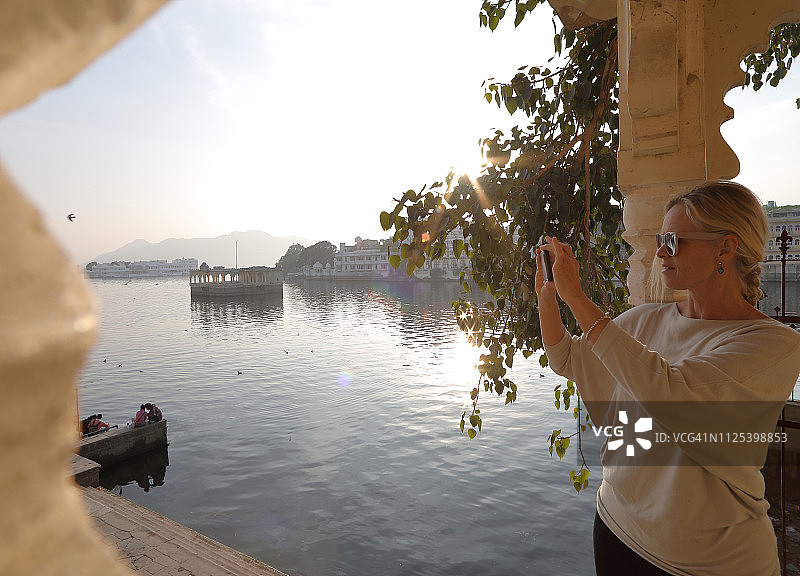 女人在湖上用智能手机拍照图片素材
