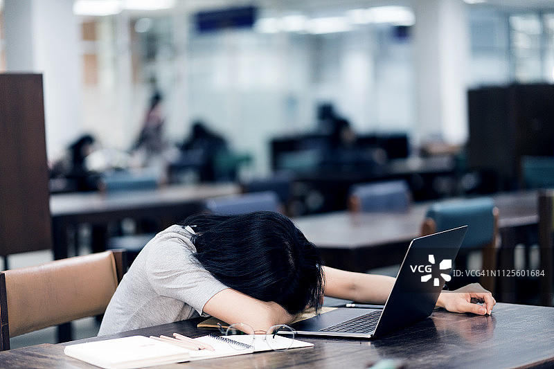 亚洲女性非常疲惫后工作与笔记本电脑图片素材