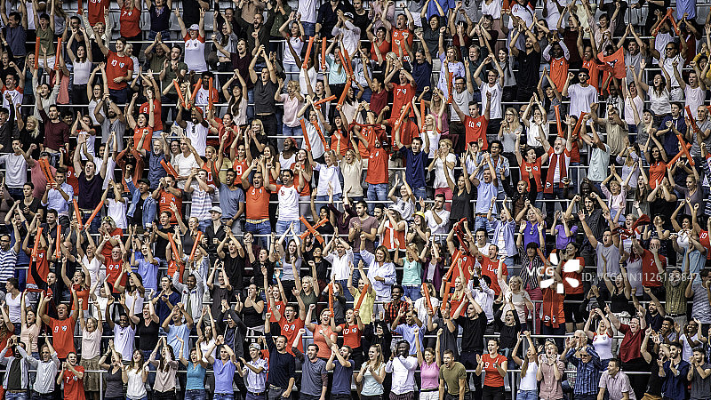穿着红色运动衫的体育迷们在体育场的露天看台上欢呼图片素材