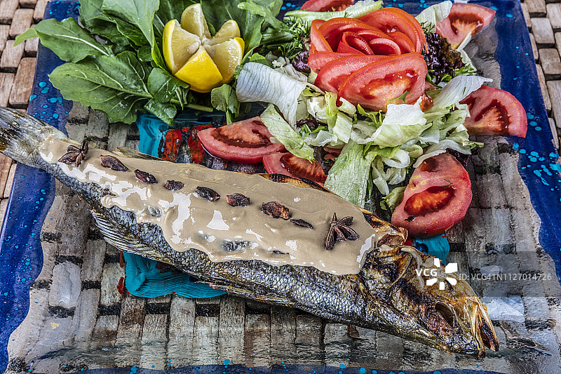 新鲜的鲈鱼。地中海风味的鱼，在煤炉中完全烤制，配以香草和柠檬。图片素材