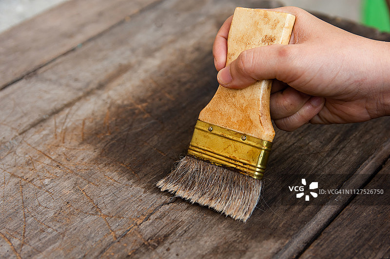 手拿刷子油漆木质木板表面与木材染色图片素材