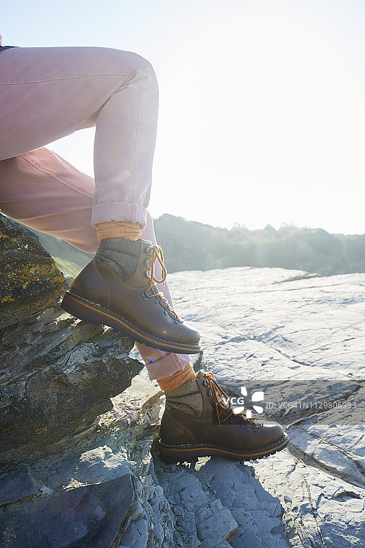 穿着登山靴坐在岩石上的女人图片素材