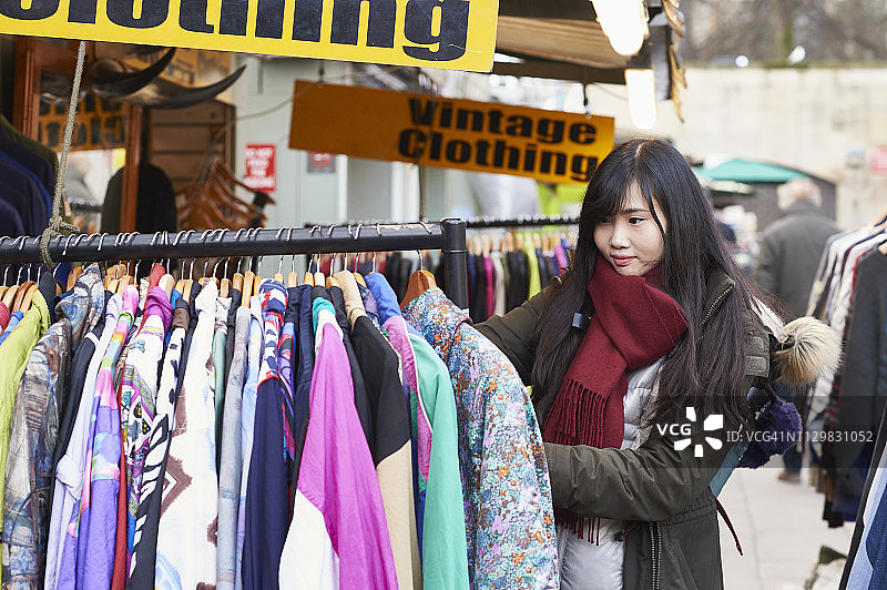 一个年轻的女人在市场上买复古衣服图片素材