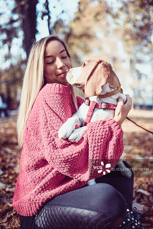 可爱的金发和她的狗在公园里拥抱图片素材