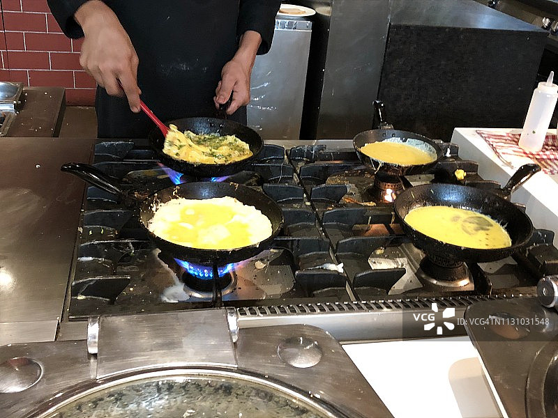 这是印度早餐餐厅厨师在煤气灶上用黑色小煎锅煎蛋的图片图片素材