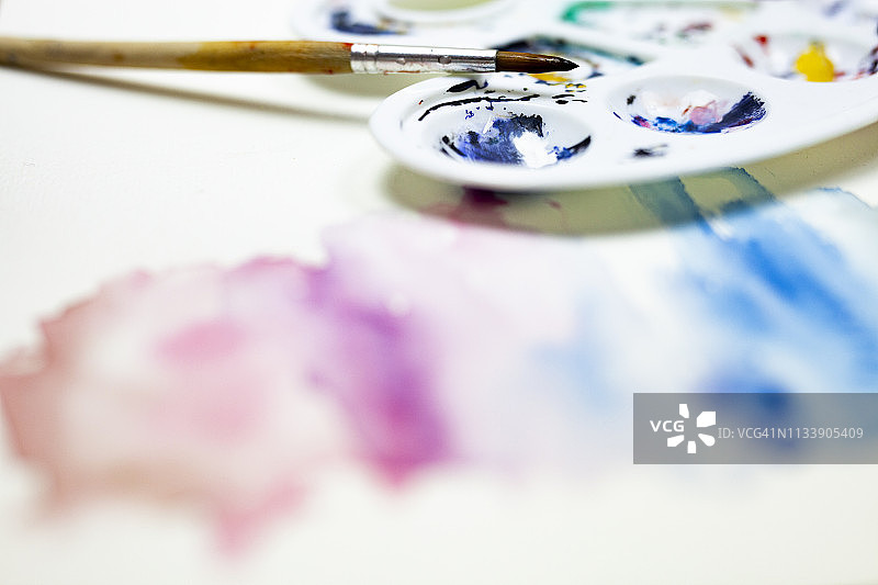 水彩颜料在纸上混合创建一个水彩效果与油漆刷和艺术家调色板图片素材