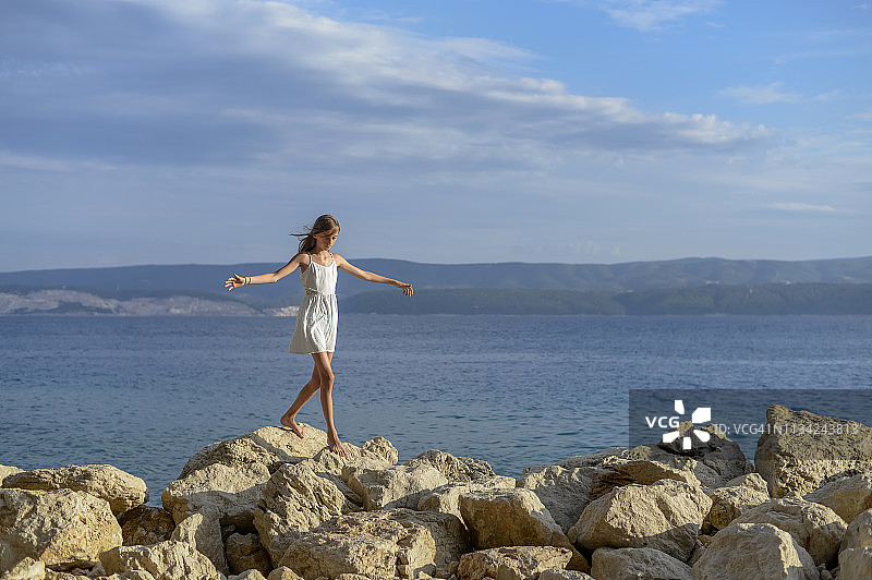 克罗地亚，Lokva Rogoznica，女孩赤脚在岩石上保持平衡图片素材