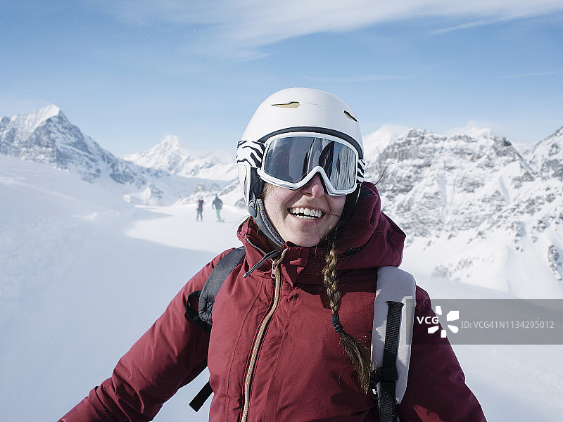 年轻女子滑雪者戴着头盔和滑雪镜微笑在白雪覆盖的风景，肖像，阿尔卑斯恰姆波里诺，皮埃蒙特，意大利图片素材