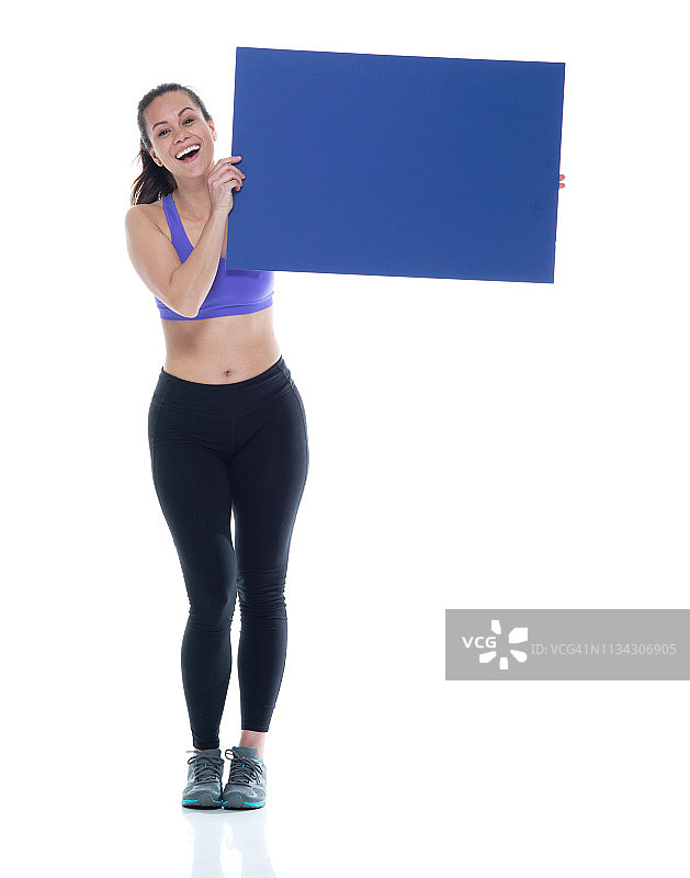 身着运动服的美女正举着一个蓝色的空白标志图片素材