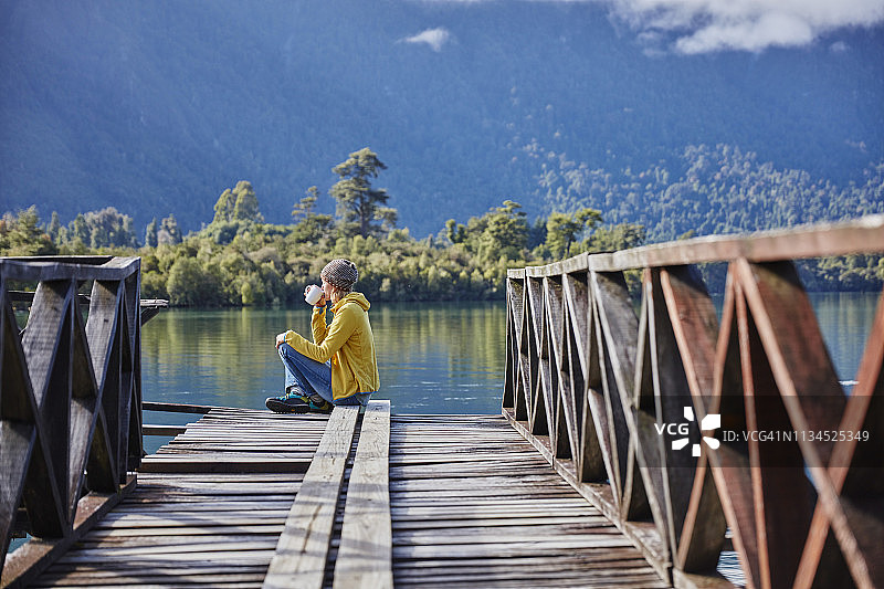 智利，Chaiten, Lago Rosselot，一个女人坐在码头上喝着马克杯图片素材