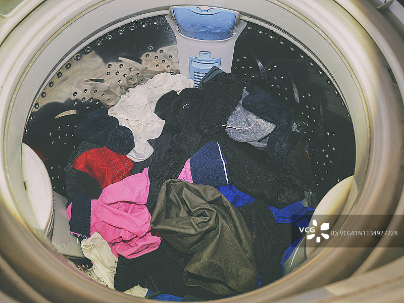 上载洗衣机洗衣服。内部视图的洗衣机滚筒在洗涤期间。前视图。图片素材