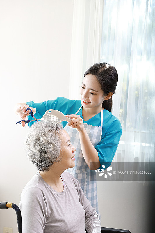 护工给一位年长的女士剪头发图片素材