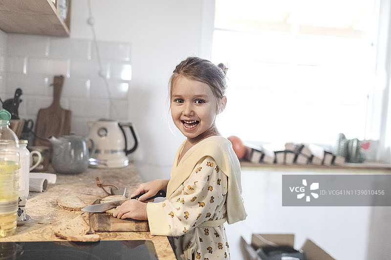 一个笑着的小女孩在厨房切面包图片素材