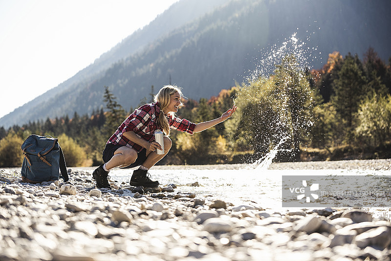 奥地利，阿尔卑斯山，女人在徒步旅行溅水在小溪图片素材