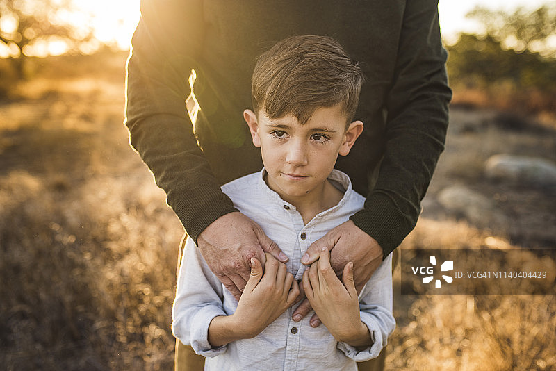 小男孩被父亲在加利福尼亚田野拥抱的特写图片素材