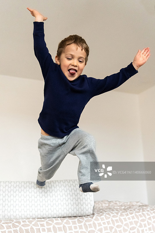 笑三岁的小男孩在床上跳图片素材