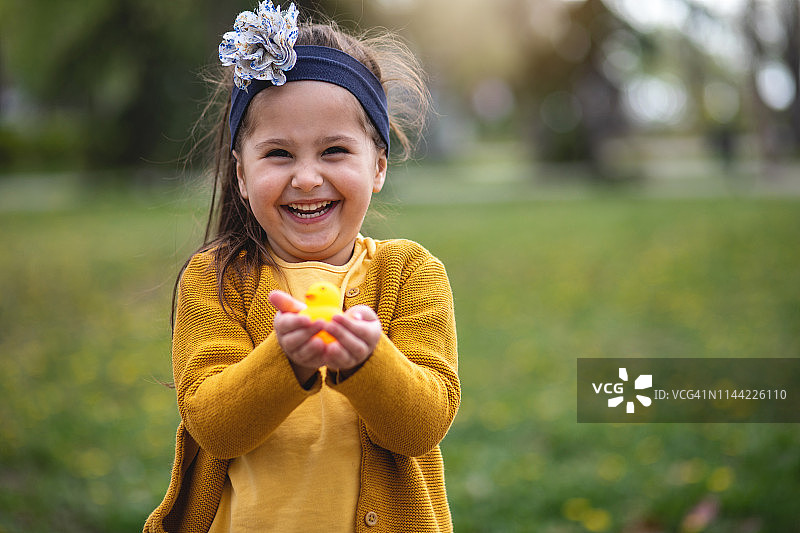 快乐的小女孩抱着一只黄色的玩具小鸭图片素材