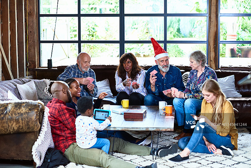 家人在圣诞节玩纸牌游戏和使用电子设备图片素材