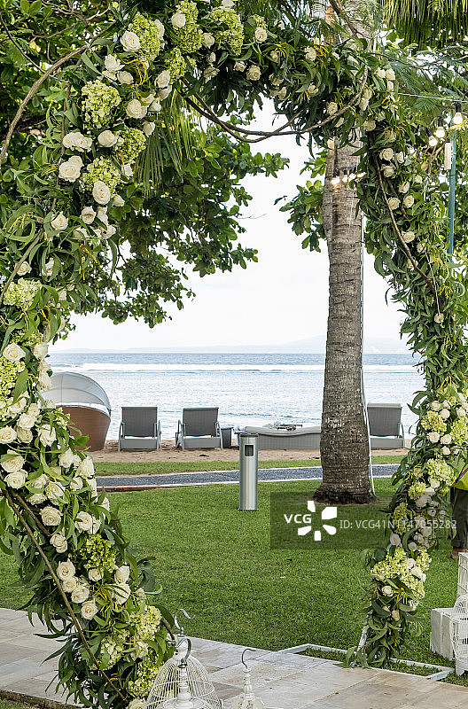 婚礼拱门装饰的鲜花户外。漂亮的婚礼布置。婚礼在花园里的绿草坪上举行。节日装饰的一部分，插花。图片素材