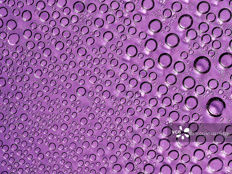 由气泡和水滴形成的纹理的完整框架，在紫色的背景上。图片素材