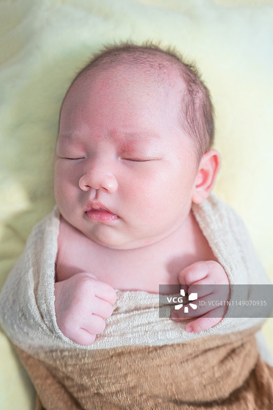 一个亚洲新生儿裹着布睡觉图片素材