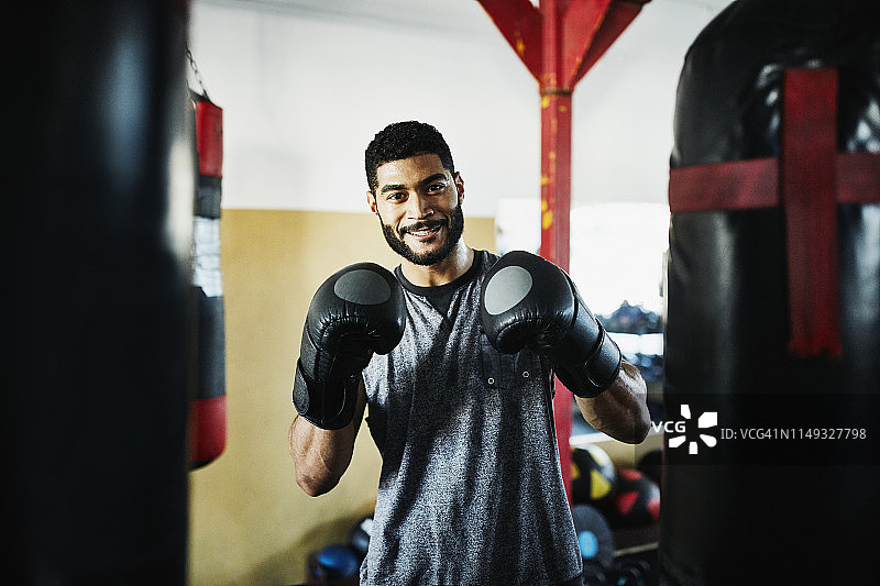 在拳击馆里戴着手套微笑的男性拳击手的肖像图片素材