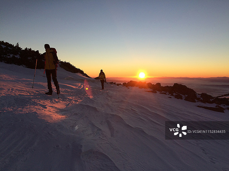 登山者的剪影。日落时壮丽的山景图片素材