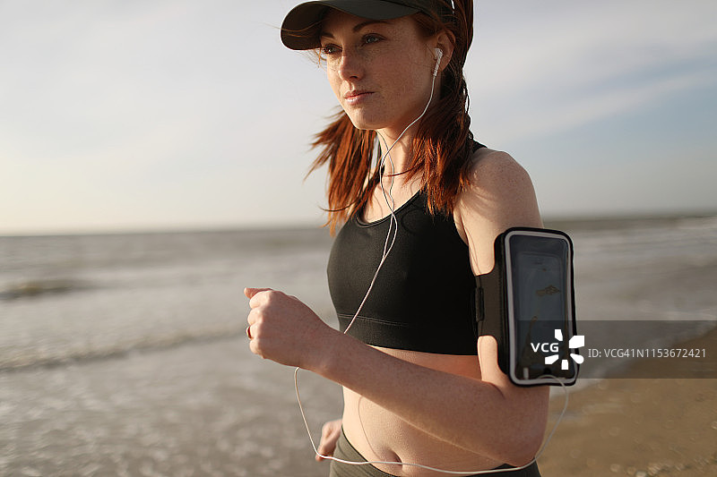 一个年轻女子在海滩上跑步图片素材