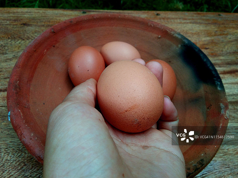 农村木材上的一个陶土碗里的鸡蛋特写图片素材