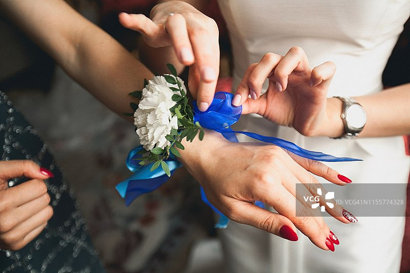 近距离拍摄，新娘向她的朋友展示手上的胸花。新娘的早晨，结婚的日子。图片素材