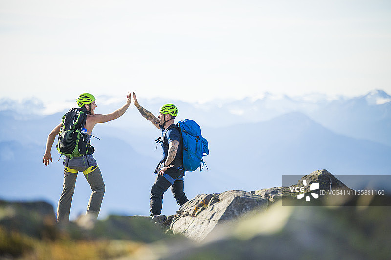 两名登山者在加拿大公元前道格拉斯峰的山顶击掌。图片素材
