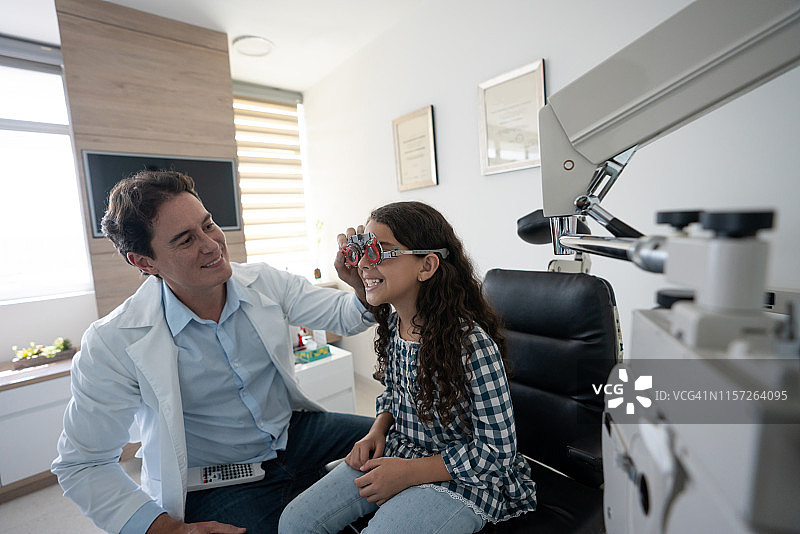 快乐的女孩在眼科医生那里检查她的眼睛图片素材