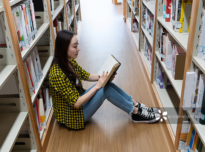 一个女人坐在图书馆的地板上看书图片素材