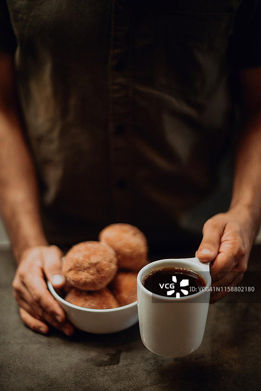 咖啡师将黑咖啡和甜甜圈放在咖啡柜台上，裁剪浅焦点图片素材