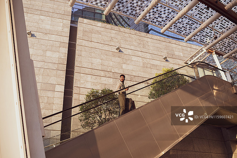 意大利米兰，伦巴第，商人登上办公大楼的自动扶梯图片素材