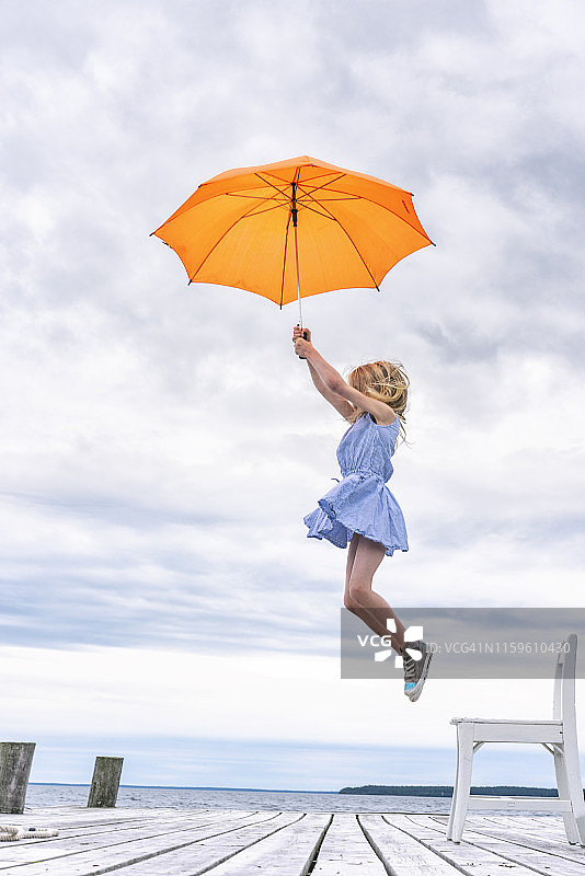 女孩被伞从椅子上抱起来图片素材