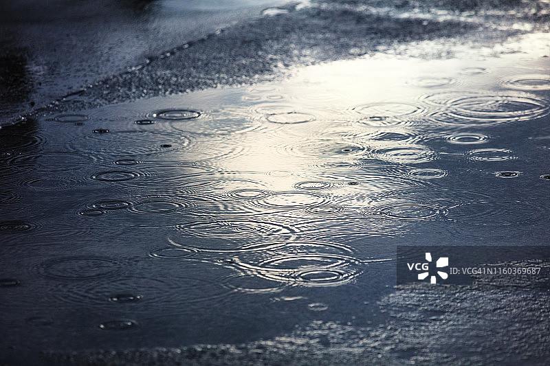 雨在城市的人行道上形成水坑图片素材