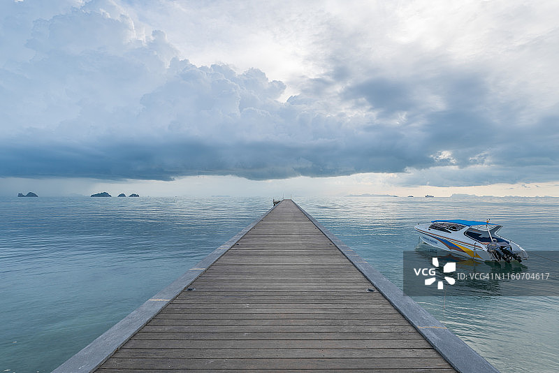 泰国苏梅岛多云天空下的海景，有一座木桥入海，还有一艘小游艇图片素材