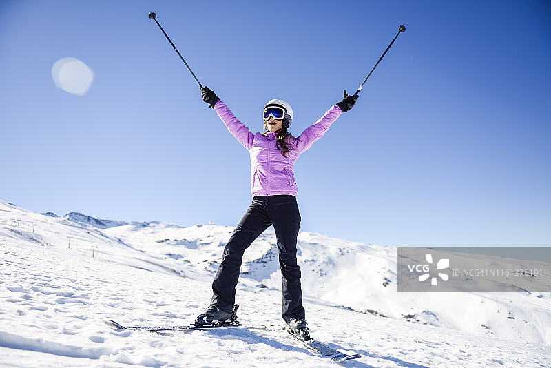 在西班牙安达卢西亚的内华达山脉，快乐的女人举起她的滑雪杆图片素材