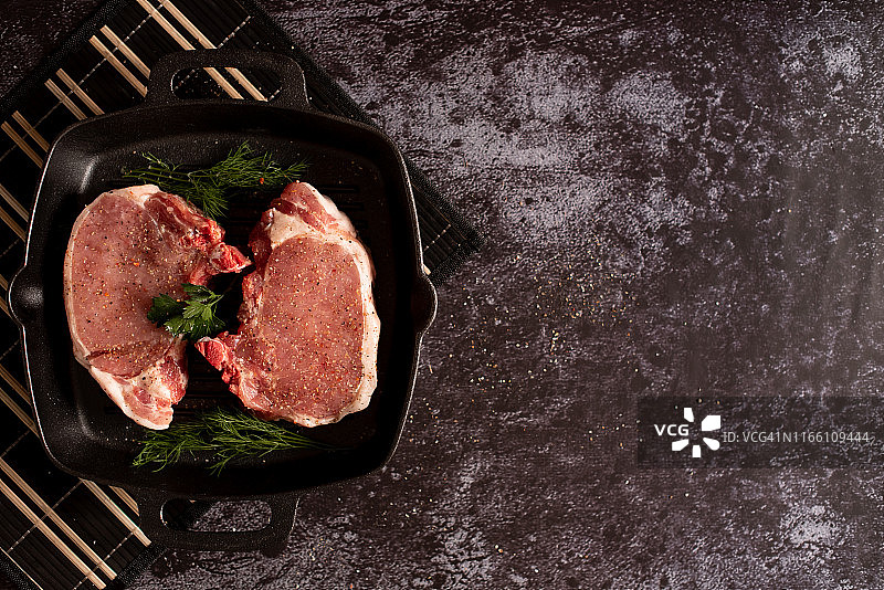 生的新鲜大理石肉牛肉在烧烤锅上准备烹饪在一个蓝色的混凝土背景俯视图图片素材