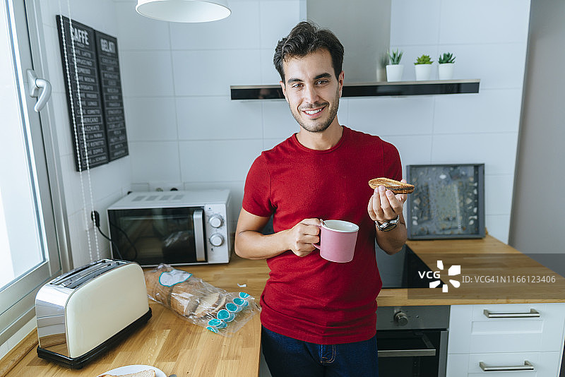 一个男人在家庭厨房里拿着烤面包和咖啡图片素材