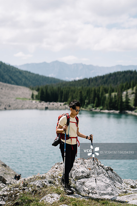 女性徒步旅行者站在湖泊和森林前面的一座山上图片素材