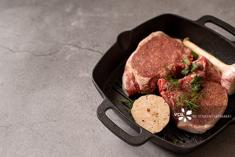 生的新鲜大理石肉牛肉在烧烤锅上准备烹饪在一个蓝色的混凝土背景俯视图图片素材
